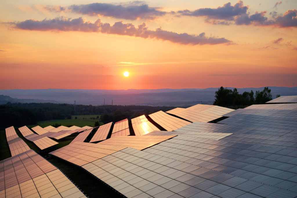 Photovoltaic panels of solar power station in the landscape at sunset. View from above.